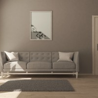Salon dans les tons beiges avec un canapé, une plante et une porte en bois