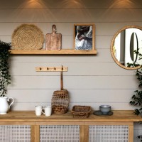 Décoration intérieure naturelle avec étagère en bois, plantes vertes, objets en osier et miroir rond mural