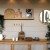 Décoration intérieure naturelle avec étagère en bois, plantes vertes, objets en osier et miroir rond mural